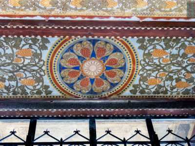 ...e, in un tripudio di colori accesi, un raffinato decoro circolare centrale a forma di rosone con otto grappoli rossi
